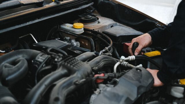 Person in Black Jacket Working on the Engine of the Car