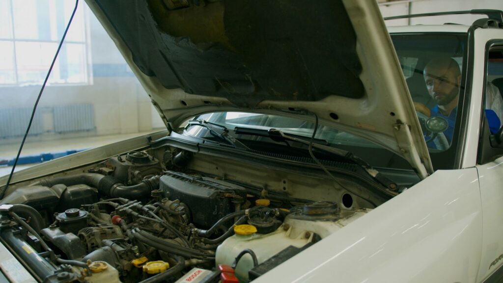 Car with open hood in garage during inspection