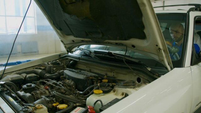 Car with open hood in garage during inspection