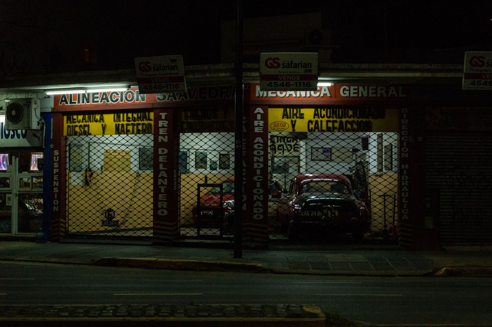 Local auto repair garage storefront at night with red car inside