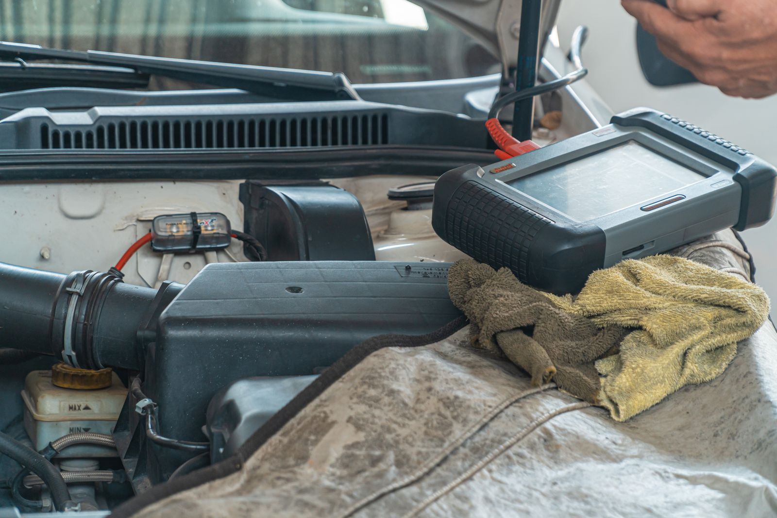 Mechanic using diagnostic scanner on car engine during inspection